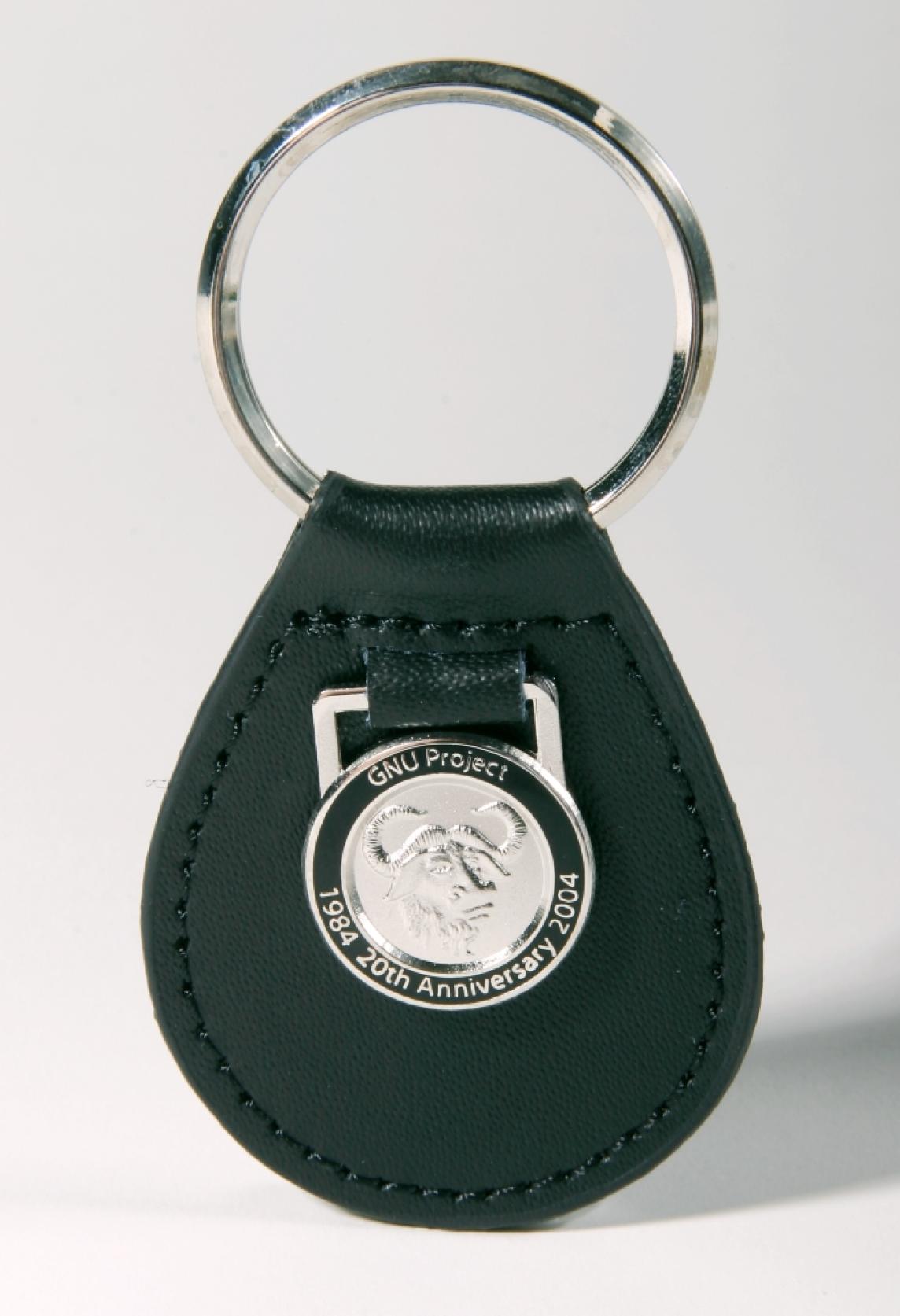 A black leather keychain with a silvery metallic gnu emblem