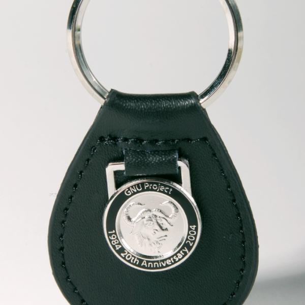 A black leather keychain with a silvery metallic gnu emblem